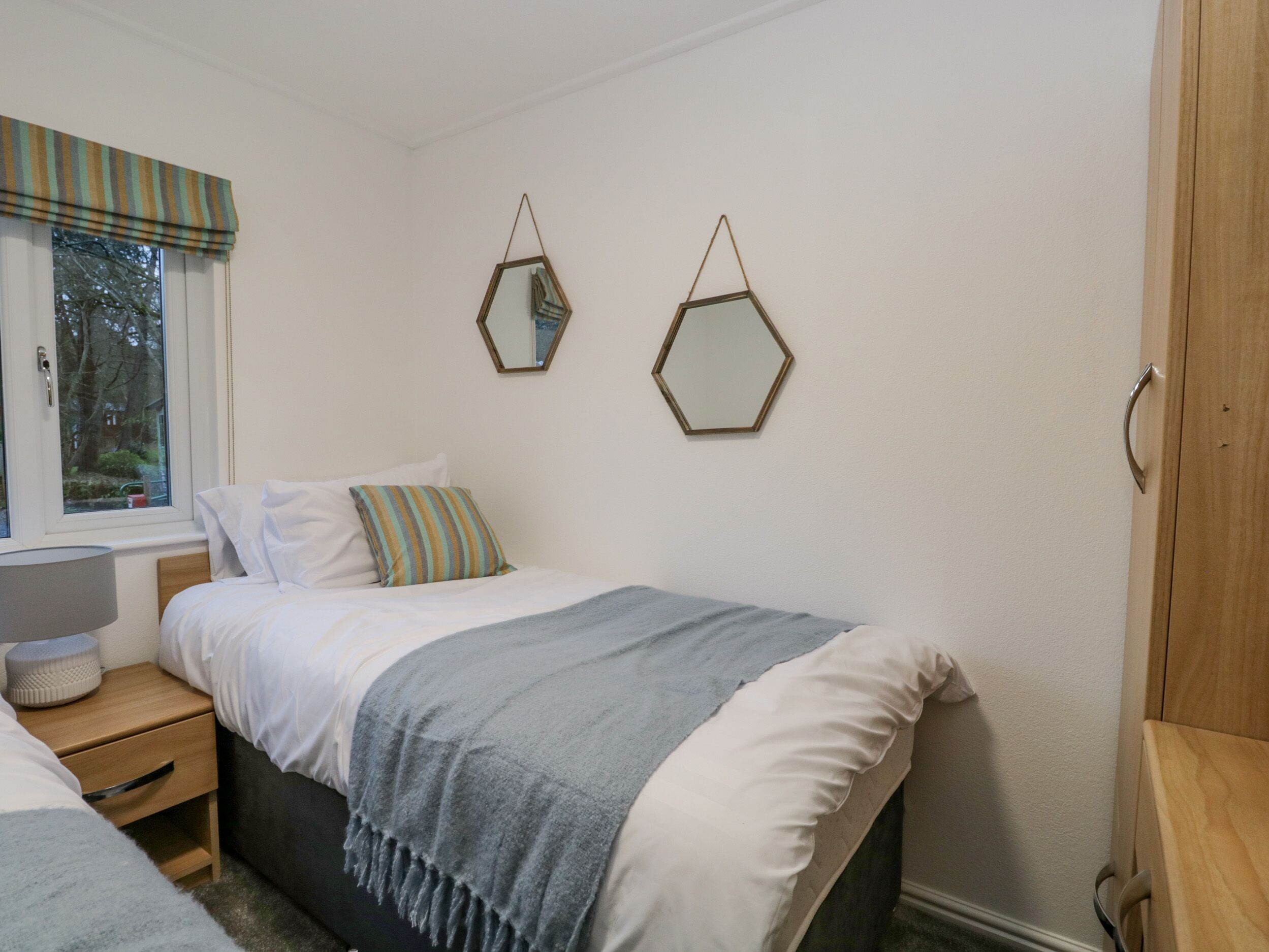 A bedroom with a bed, bedside table, and a window with curtains.