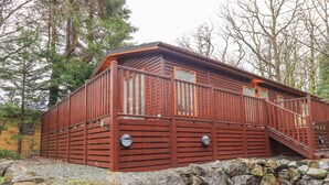 A cabin with a wooden exterior, a stone foundation, and a metal gate. - 25 Thirlmere (Windermere)
