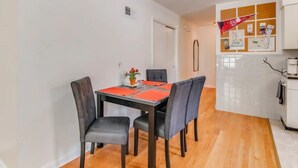 A dining area with a table set for four, surrounded by chairs, in a room with wooden flooring and white walls. - Spacious | Quiet | 1 bedroom duplex w free parking! (St. Louis)