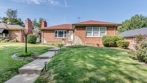 A single-story brick house with a red roof, a front porch, and a well-maintained lawn. - Spacious | Quiet | 1 bedroom duplex w free parking! (St. Louis)