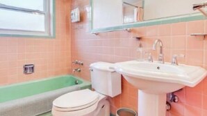 A bathroom with a bathtub, toilet, sink, and a window. - Spacious | Quiet | 1 bedroom duplex w free parking! (St. Louis)