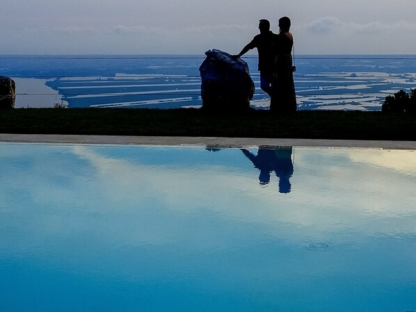 Una pareja parada junto a un estanque reflectante, con vistas a una gran extensión de agua.