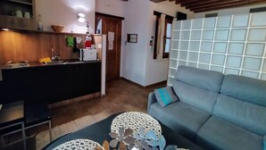 Una cucina moderna con travi in legno, un divano grigio e un tavolino rotondo.