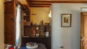 Una cucina compatta con mobili in legno, un tavolino e un bollitore rosso.
