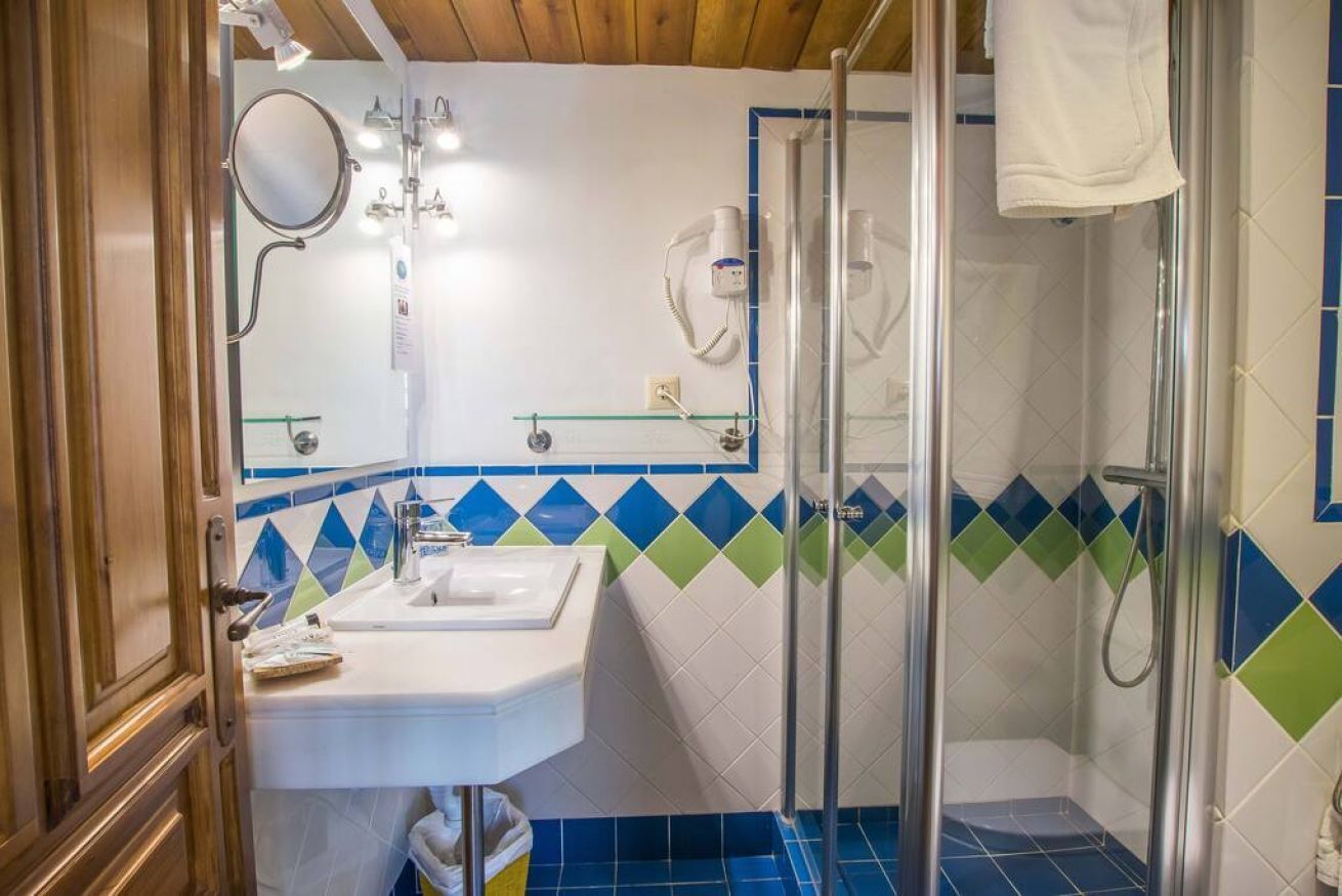 Un baño con ducha, lavamanos y espejo.