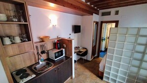 Une cuisine de taille réduite équipée d’un four à micro-ondes, d’un évier et de meubles de rangement en bois.