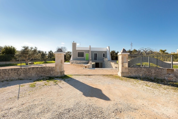 Una casa moderna con entrada de piedra, puerta verde y portón de metal.
