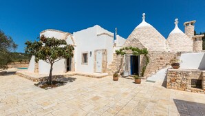 A white building with stone domes and a tiled courtyard. - 2530 Trullolive by Perle di Puglia (Ostuni)