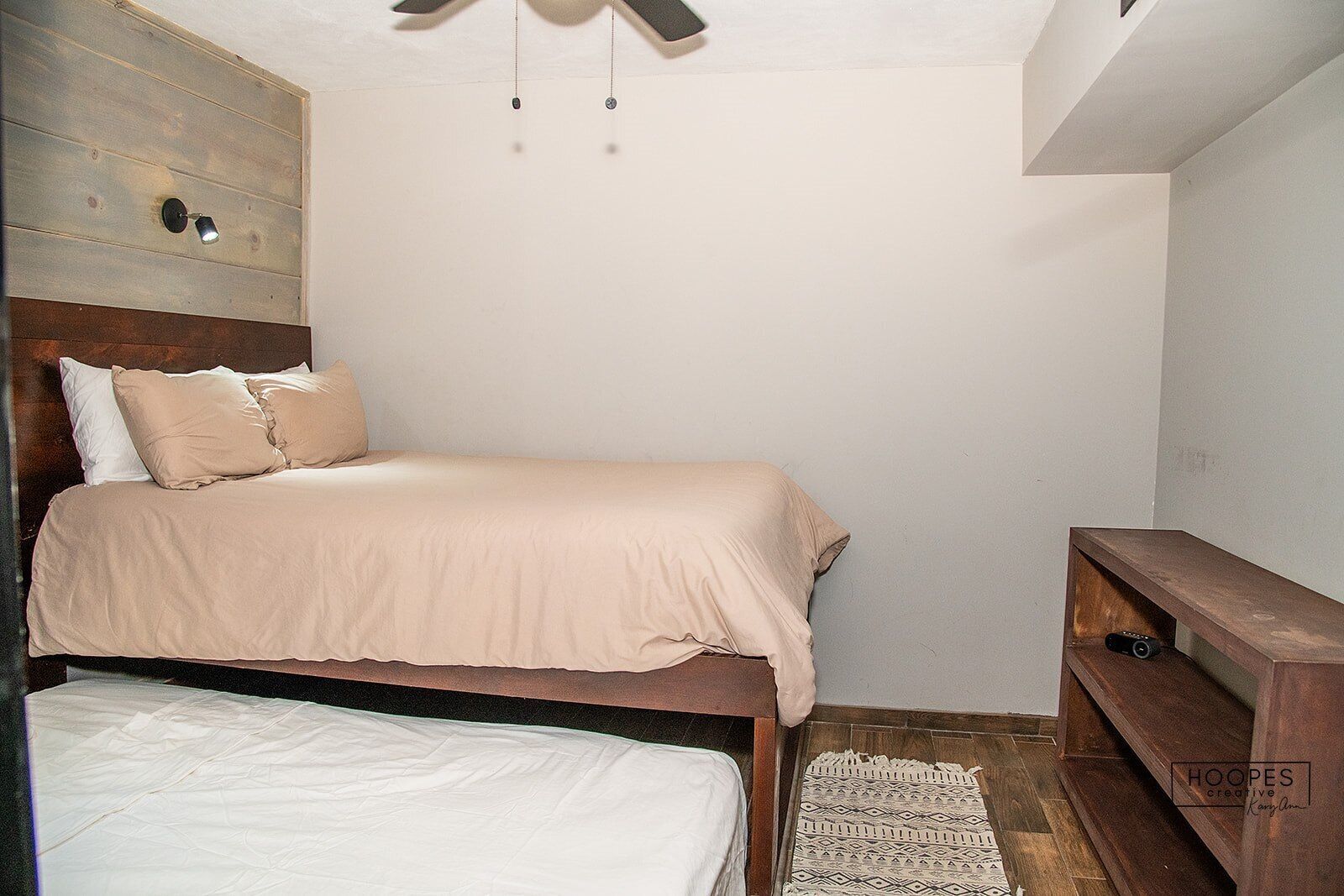 A bedroom with a bed, bedside table, and a ceiling fan.