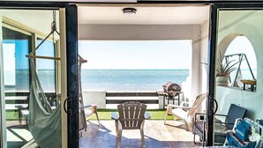 Une pièce avec vue sur l’océan, un hamac, un barbecue et du mobilier d’extérieur.