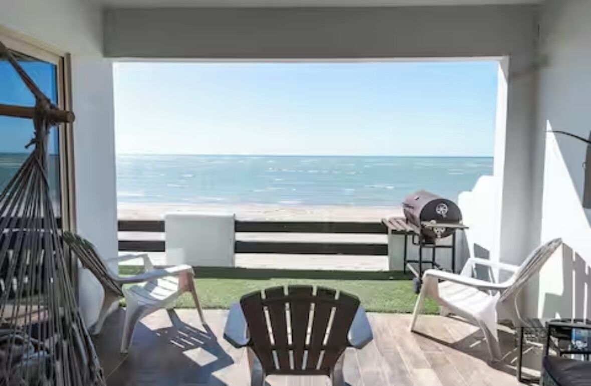 Ein Balkon mit Meerblick, einem Grill und Sitzgelegenheiten im Freien.