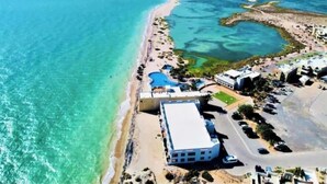 Vue aérienne d’une station balnéaire dotée d’une plage, d’une piscine et d’un parking.