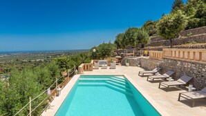 A pool area with lounge chairs and a stone wall, overlooking a scenic landscape. - 2522 Trullo Monte Cannone - Appartamento 2 by Perle di Puglia (Fasano)
