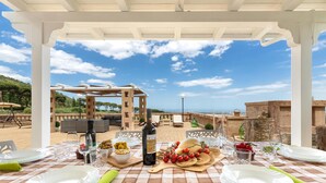 An outdoor dining area with a checkered tablecloth, white plates, and a bottle of wine. - 2522 Trullo Monte Cannone - Appartamento 2 by Perle di Puglia (Fasano)