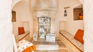 A cozy room with a stone fireplace, benches, and a small table with a lantern. - 2985 Trullo tra gli Ulivi by Barbarhouse (Carovigno)