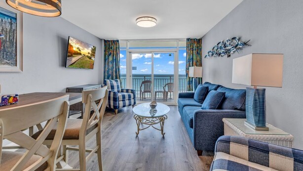 Een moderne woonkamer met balkon, een eethoek en een bank.