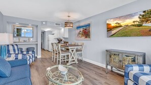 Een moderne woonkamer met een eethoek, een glazen salontafel en uitzicht op het buitenleven.
