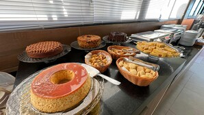 A buffet with various desserts and snacks, including cakes and pastries, arranged on a counter. - POUSADA AMADA TERRA (Ipojuca)