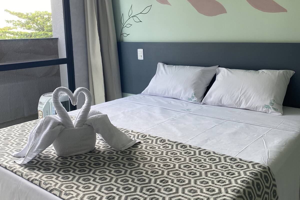 Una habitación de hotel con una cama, un ventanal y una pared con diseño de hojas.