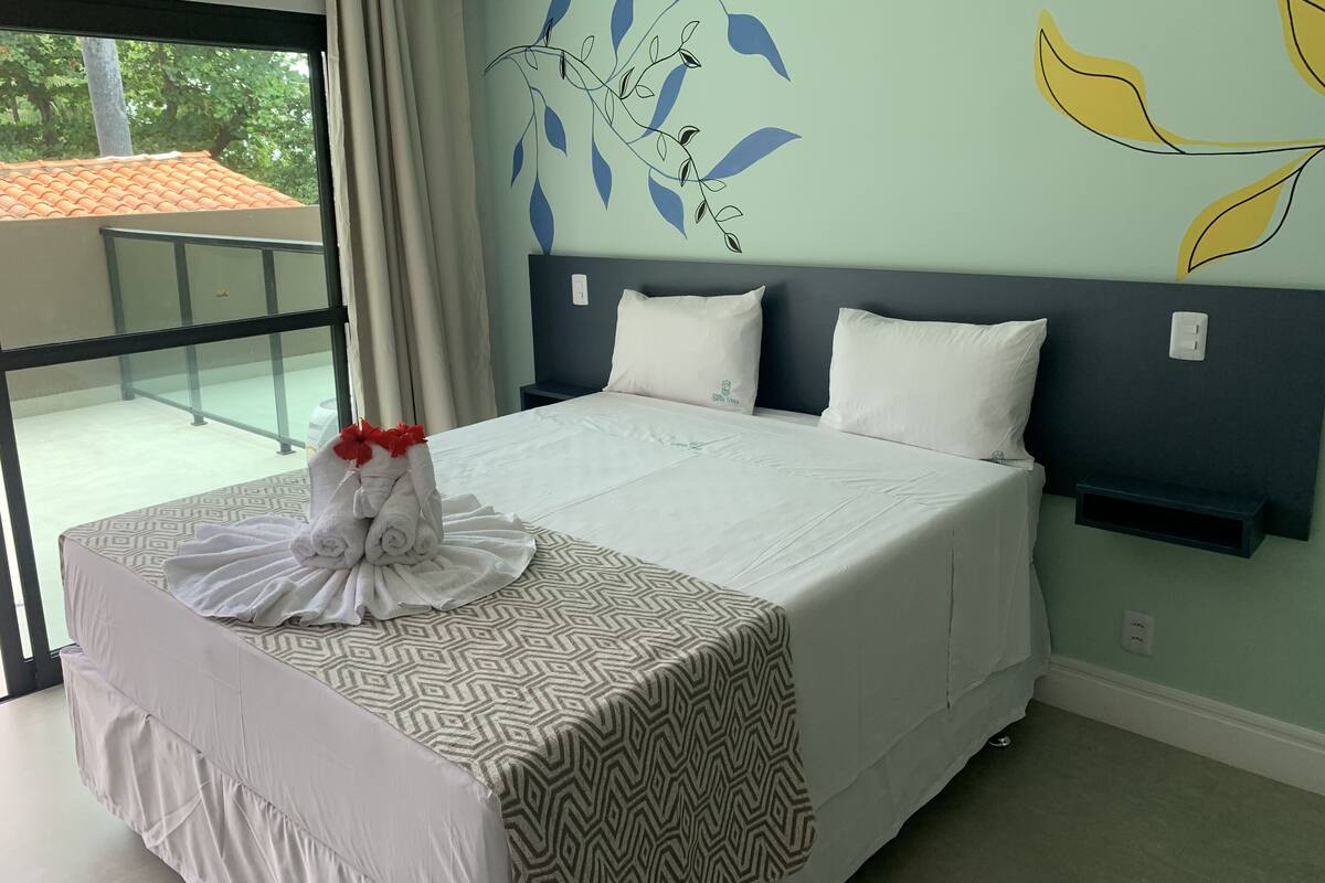 Una habitación de hotel con cama, vistas al exterior y una pared decorada con motivos de hojas.