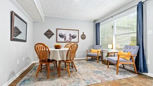 Un área de comedor con una mesa, sillas y una alfombra.