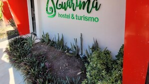 Un letrero de hostal con el nombre 'Guarimã' y la inscripción 'hostal & turismo' debajo.