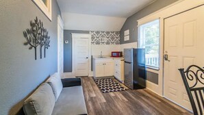 A compact kitchen with white cabinets, a refrigerator, and a microwave.