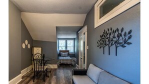 A hallway with a dining area, a sofa, and a bedroom with a window.