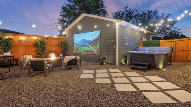 Un jardin arrière accueillant avec un jacuzzi, des sièges d’extérieur et un grand écran pour se divertir.