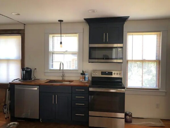 A modern kitchen with dark cabinets, a stainless steel dishwasher, a built-in oven, and a microwave.