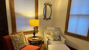 Una sala de estar acogedora con un sillón rojo, un sofá blanco y una mesita redonda con una lámpara.