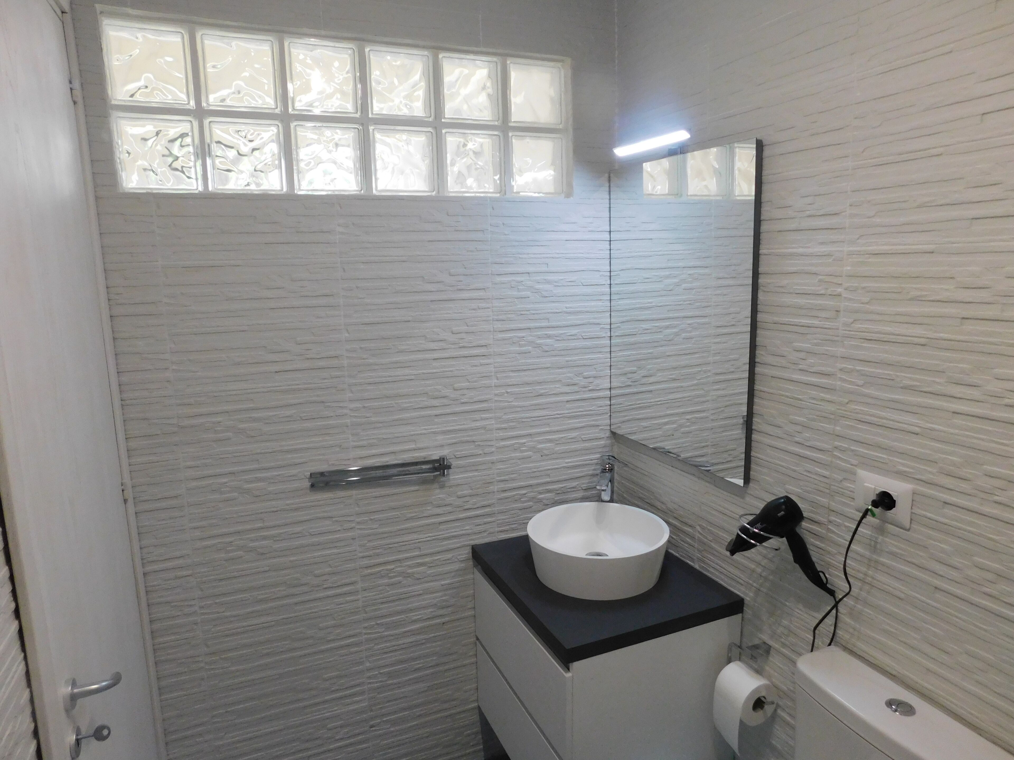 A bathroom with a white sink, a mirror, and a toilet.