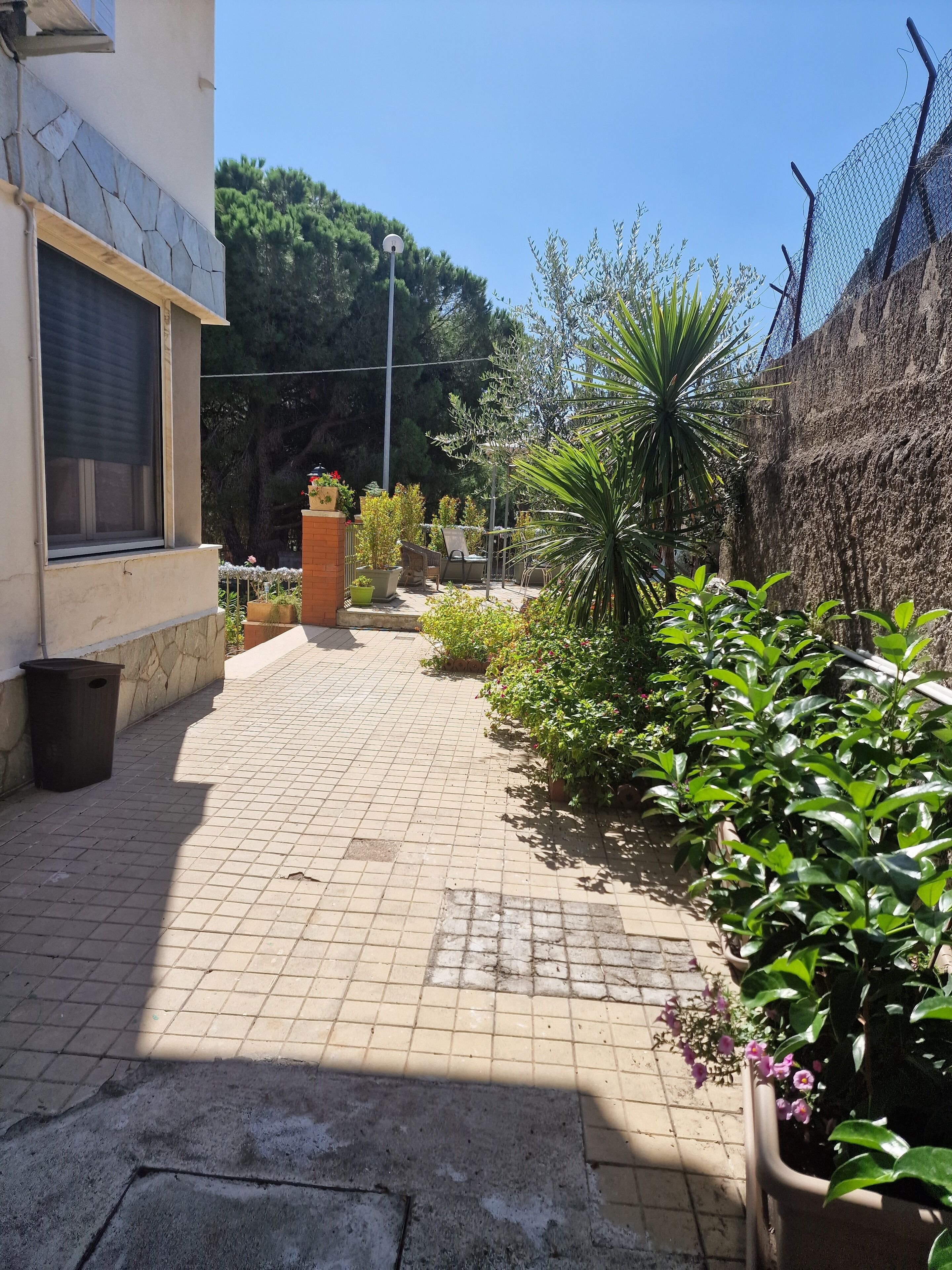 Un patio empedrado con macetas, un espacio de descanso y un muro de ladrillo.