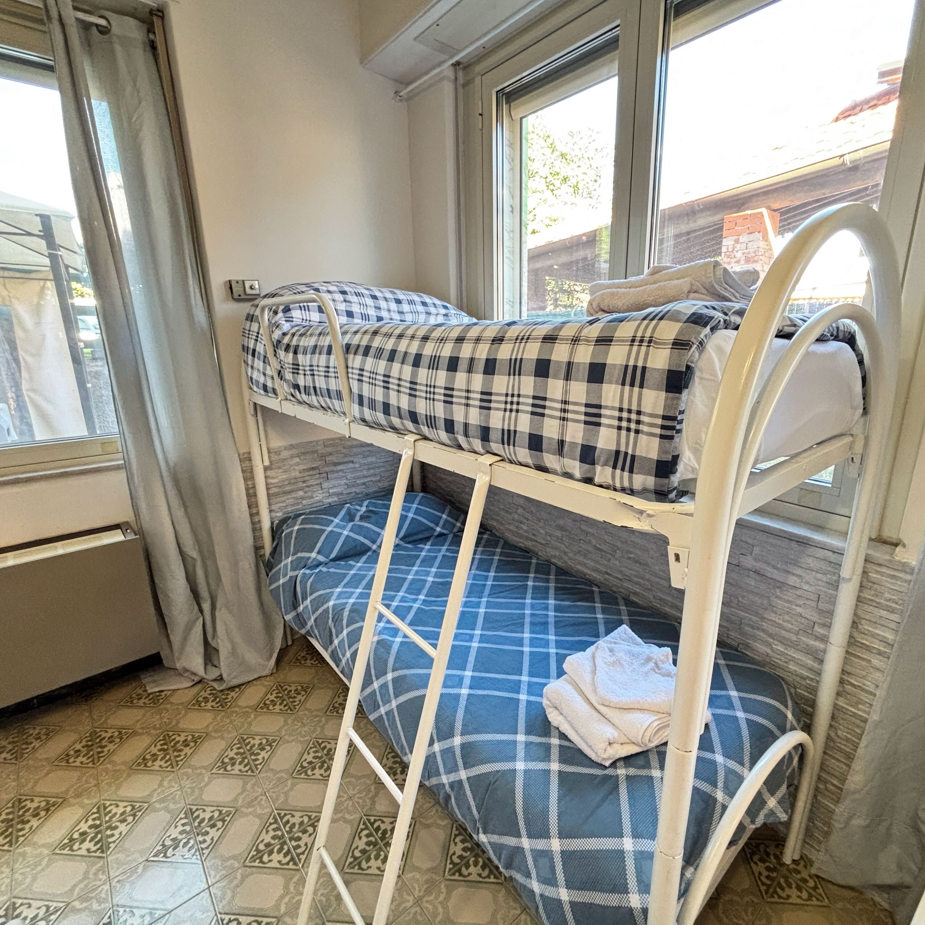 Een stapelbed met een geruit sprei en een blauw kussen.