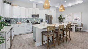 A modern kitchen with white cabinets, a large island, and pendant lighting. - Serenity retreat * the ultimate luxury getaway (Naples)