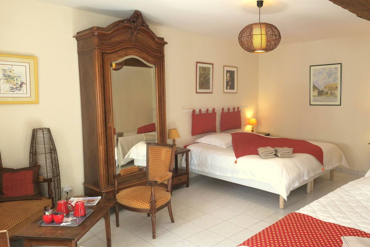 A hotel room with two beds, a wooden chair, a table with red cups, and a large mirror.