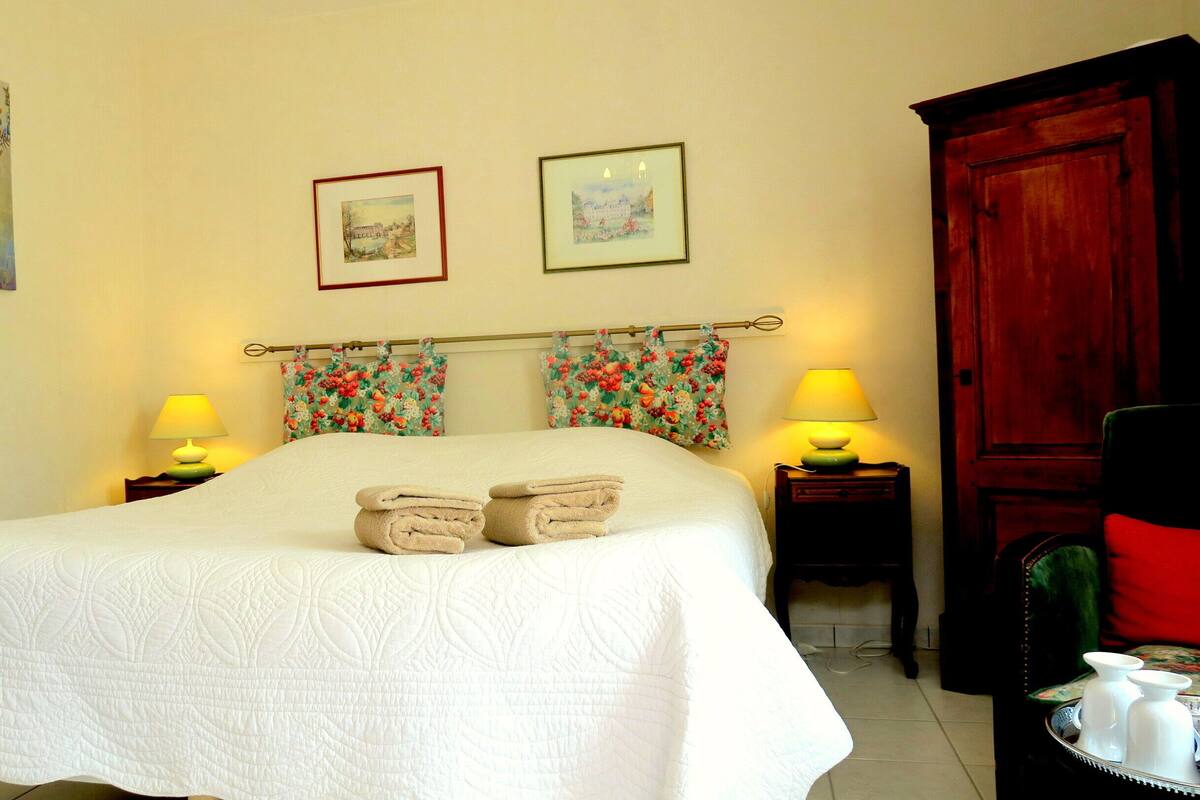 A neatly made bed with a white quilt, two lamps on bedside tables, and two framed pictures on the wall.