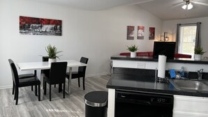 Une cuisine moderne équipée d’un lave-vaisselle, d’un évier et d’un coin repas avec des chaises et une table.