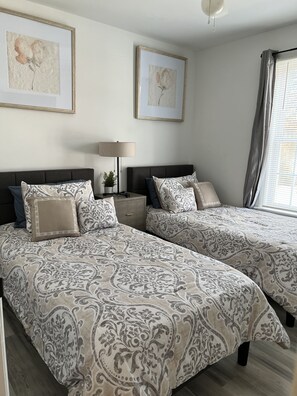 A bedroom with two beds, a bedside table with a lamp, and two framed artworks on the wall. - Relaxing Red Velvet 5 Minutes to Downtown Raleigh & NC STATE (Raleigh)