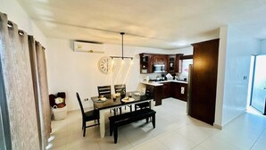 Cozinha moderna com armários de madeira escura, mesa de jantar com cadeiras e forno embutido.