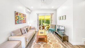 Una sala de estar con sofá, mesa de centro, televisor y obras de arte.