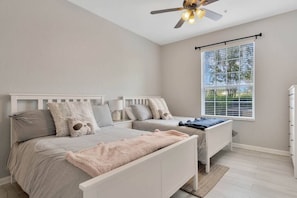 A bedroom with two beds, a ceiling fan, a window with blinds, and a dresser.