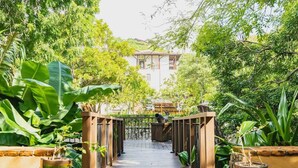 A wooden pathway leading to a building surrounded by lush greenery. - Steps to beach in the heart of Las Catalinas (Las Catalinas)