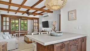 A spacious living area with a large wooden ceiling, a dining table, and a kitchen island with cabinets. - Steps to beach in the heart of Las Catalinas (Las Catalinas)