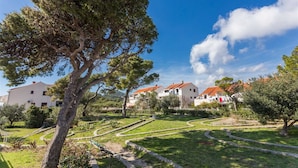 A residential area with white houses and red roofs, surrounded by green lawns and trees.