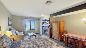 Une pièce confortable avec un grand lit, une petite table, un canapé, une cheminée et une table à manger avec des chaises.
