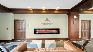 Un hall d’entrée doté d’un grand téléviseur à écran plat diffusant une image de feu de cheminée, d’un comptoir de réception et d’un espace salon avec un canapé et des fauteuils.