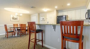 Una cocina con barra, sillas de madera y una mesa de comedor.