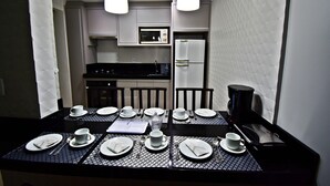A dining area with a table set for four, equipped with plates, cups, and cutlery. - MORADA PINHEIRO (Bombinhas)
