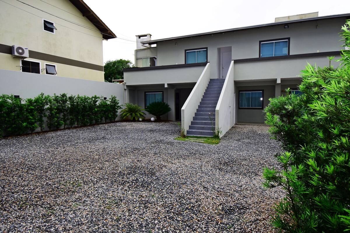 Un bâtiment moderne doté d’une cour en gravier, d’un escalier et d’un petit jardin.